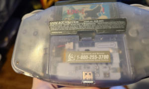 Translucent, light purple, slightly oval-shaped slab with a informational label and an opening for a usb cable.