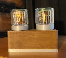 Two glass tubes sit on a wood box. The numbers '7' and '1' glow orange from behind metal grids inside the tubes.