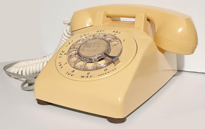 An off-white trapezoid with a circular dial on the front, a handle with two bulbous ends rests on top.